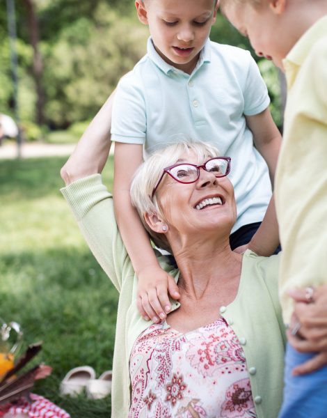 Loving senior woman embracing her grandchildren with a cheerful smile on her face